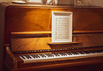 Fototapeta na wymiar wooden piano with sheet music in a picture frame 