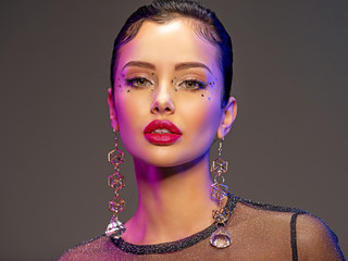 Portrait of beautiful young woman with bright makeup. Shiny sequins on face. Beautiful brunette...