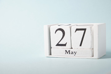 Wooden calendar on a blue background with the date of May 27