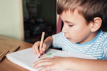 Cute boy drawing picture in album