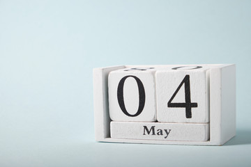 Wooden calendar on a blue background with the date of May 4