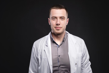 Obraz premium Portrait of a young intern doctor. A man is standing in a photo studio. Making a diagnosis. Studio portrait