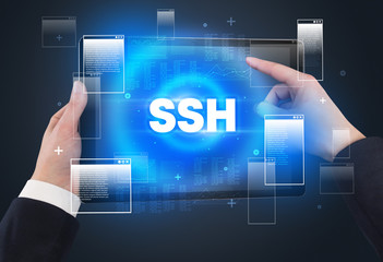 Close-up of a hand holding tablet with SSH abbreviation, modern technology concept