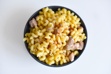 boiled macaroni with meat on a plate on a white background