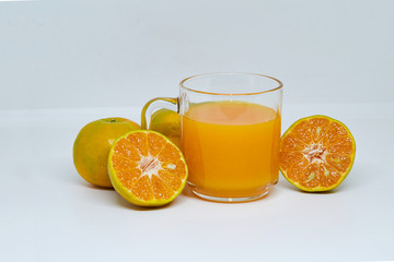 Orange juice in glass cup with sliced orange ripe on white background. Close up and selective focus, copy space.