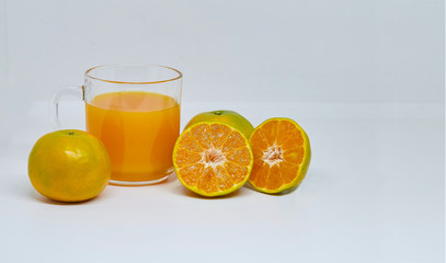Orange juice in glass cup with sliced orange ripe on white background. Close up and selective focus, copy space.