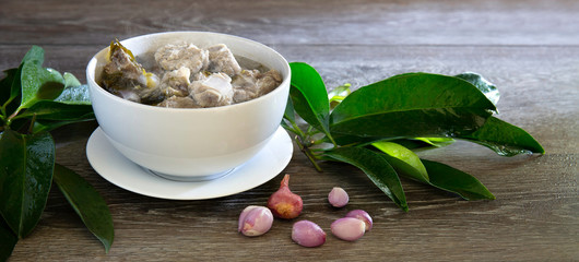 Boiled Rib pork with Chamuang leaves (thai food) in white bowl on gray wooden table