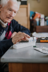 Senior arranges medicines for each day of week