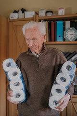 Old man holding two packs of toilet paper