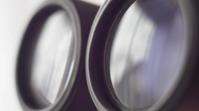 Binoculars Front Lens Reflecting Light and Clouds Close Up