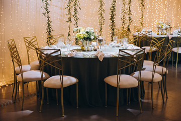 Wedding banquet. Table setting. Banquet tables are decorated with compositions of yellow flowers and lemons, on the tables are plates with napkins, glasses, candles and cutlery
