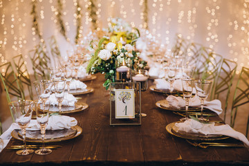 Wedding banquet. Table setting. Banquet tables are decorated with compositions of yellow flowers...