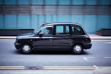 Fototapeta na wymiar A London cab speeds through a city landscape