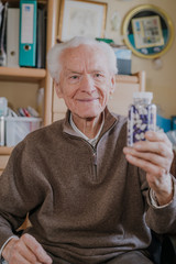Senior man holding bottle with Pills closeup
