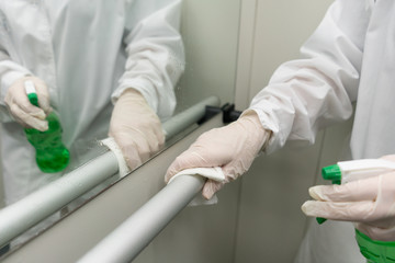 Woman using wet wipe and alcohol sanitizer spray to clean an elevator push button control panel. Disinfection, cleanliness and health care, Anti Coronavirus COVID-19