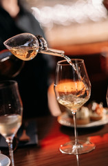 wine is poured into a glass through an aerator at a tasting in a bar