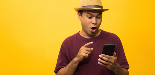 Asian man happy with his smartphone on yellow background. young man using looking at smartphone.