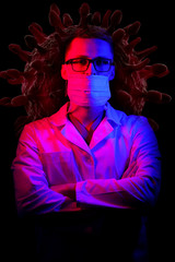 Doctor stands crosshands in medical mask. Black background with blue - red light. Doctor in glasses with medical mask on face. Virus, COVID-19 and coronavirus identification and prevention.