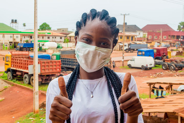 young black beautiful lady wearing a nose mask and giving thumbs up
