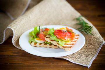 Fototapeta na wymiar fried bread toast with salad leaves and salted red fish
