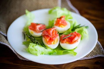 boiled eggs with salted red fish and salad leaves
