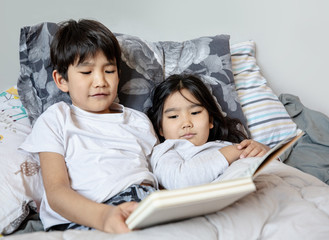 children in bed reading book
 