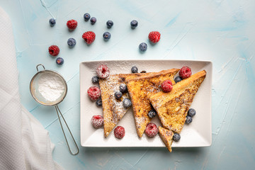 French toast with cinnamon and fresh berries on light blue background. Quick and easy breakfast,...