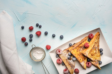 Delicious sweet French toast with cinnamon, vanilla and fresh berries on light blue background....