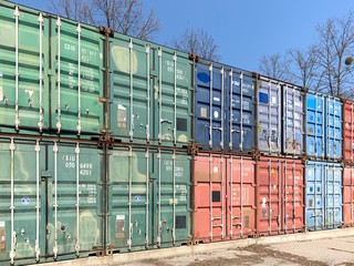Metal, industrial, multi-colored containers for transportation on ships. Stack of cargo containers in the dock, on blue sky background.
