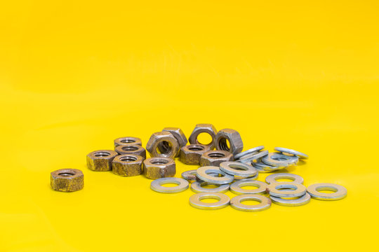 Group of old washers and rusty nuts on yellow background Fixing elements. Stock photo