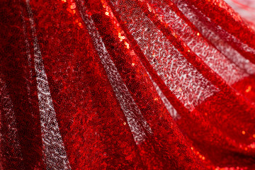 red shiny fabric with pleats on the gleam hanging folds