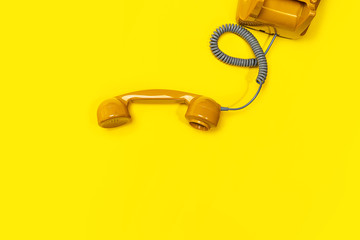Old fashioned handset on yellow color background. Modern retro style of rotary telephone.