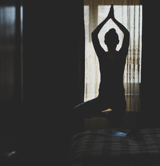 woman in a yoga pose in bedroom staying fit and mentally healthy at home