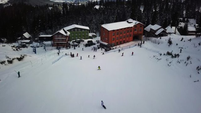 Aerial camera opener in the mountains and ski resort. Opening panoramic shoot. The camera rises above a ski resort on the background of a mountain range.