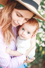 Obraz premium A young mother with a child in her arms on a walk in a blooming garden.