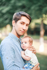 Fototapeta premium A father holds his son in his arms, in a garden