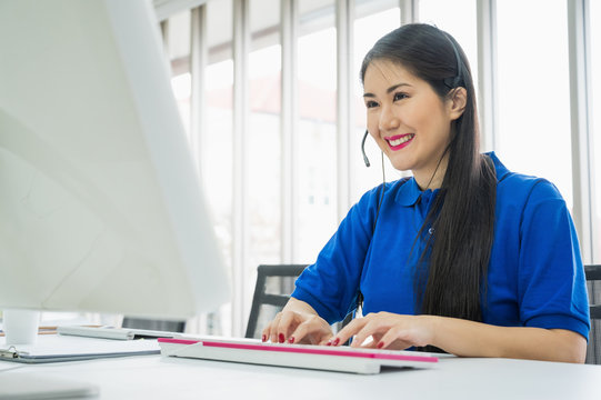 Asian female customer support operator at work. Team Business and Delivery call center in office. Working with a headset in blue uniform.