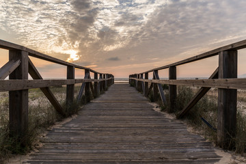 Fototapeta premium wooden walkway of the beach from which we see the sunset on a day with clouds