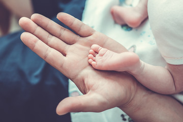 Father's hands holding small baby's feet