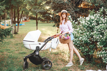 A woman is walking with a baby stroller on the path in the park at sunset.