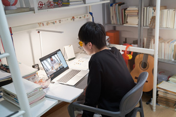 Asian kid learning from home on laptop in his bedroom