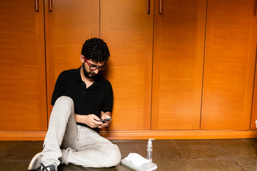 Man in his room trying to distract with cell phone during social isolation.