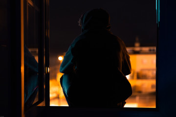 person reflecting on his home sitting at the window in quarantine for the coronavirus