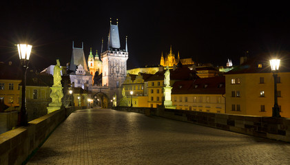 Obraz premium Night colorful Prague gothic Castle with St. Nicholas' Cathedral and Bridge Tower from Charles Bridge with its baroque Statues without People at the time of Coronavirus, Czech Republic