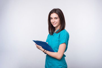 Photo of a young female doctor or dentist student is writing something on a blue paper board.