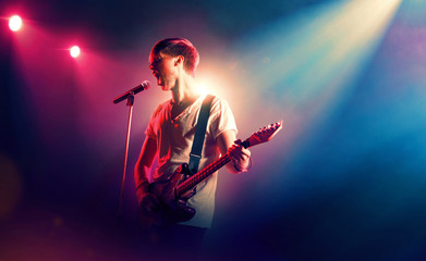 Singer with a guitar performing on floodlighted stage 