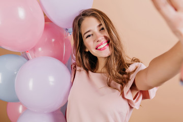 Indoor photo of cute girl with long hairstyle making selfie after birthday party. Portrait of...