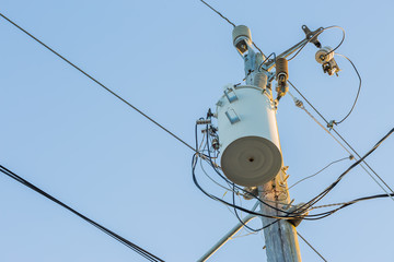 Power pole with transformer and power lines. Blue sky in the background. 