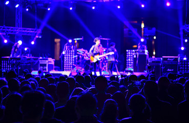 Fototapeta na wymiar Defocused concert scene. blurred lights, stage and silhouette crowd people.