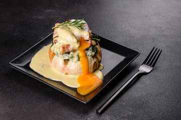 Eggs benedict or eggs florentine on a black plate in the cafe